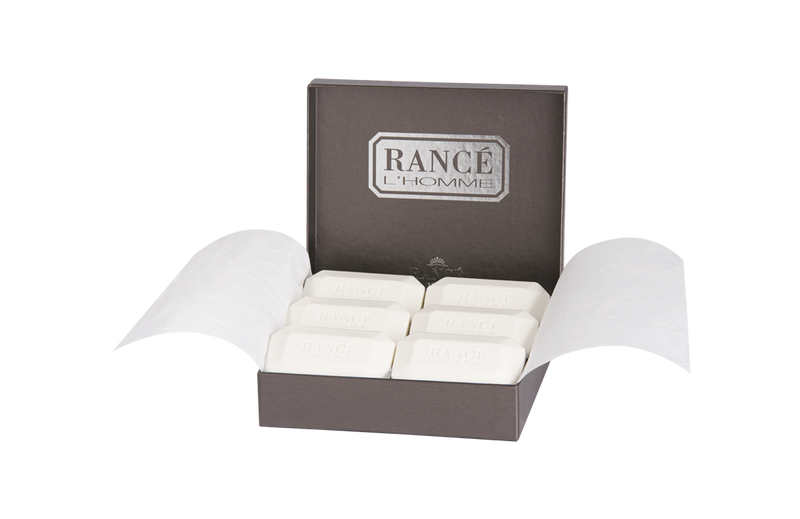 An elegant box of Rancé Classic Soap - L'Homme, showcasing six white bars neatly arranged and each embossed with the Rancé logo. The packaging reflects a premium touch.