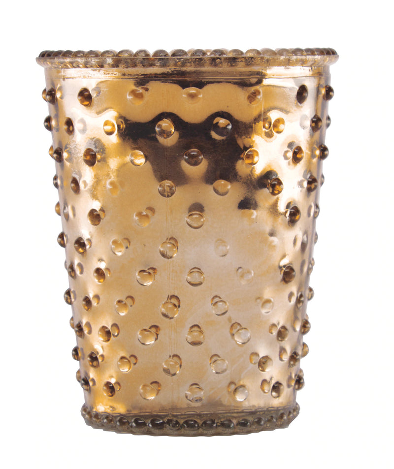 A golden Simpatico NO. 82 Latte Hobnail Glass Candle holder with a dotted design and textured bumps, containing a hand-poured soy wax candle, isolated on a white background.