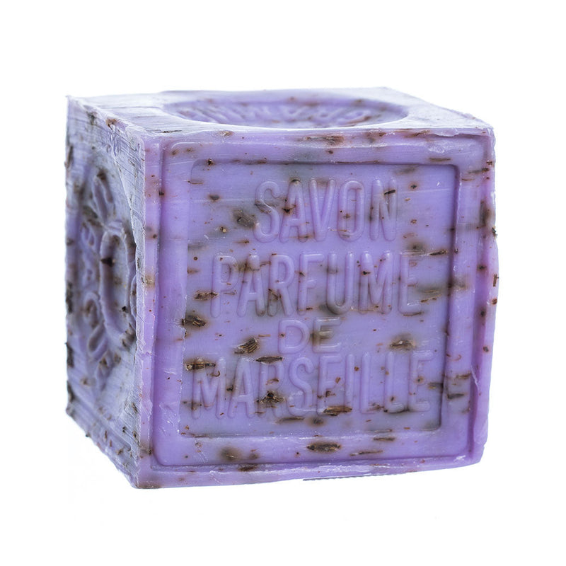 A purple, cube-shaped bar of French Soaps Savon de Marseille with Crushed Flowers - Lavender soap, containing specks and embossed lettering that reads "savon parfume de marseille", isolated on a white background.