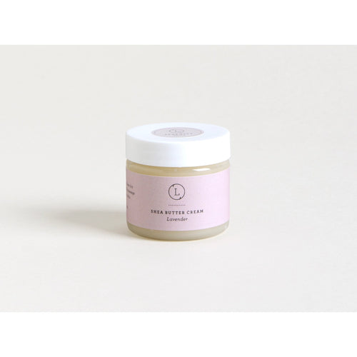 A jar of Lizush Lavender Infused Shea Butter Body Cream with a lavender label sits against a light grey background, showcasing a clear and minimalistic product design. This hydrating body lotion is perfect for daily use.