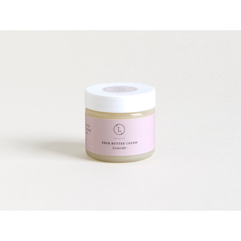 A jar of Lizush Lavender Infused Shea Butter Body Cream with a lavender label sits against a light grey background, showcasing a clear and minimalistic product design. This hydrating body lotion is perfect for daily use.