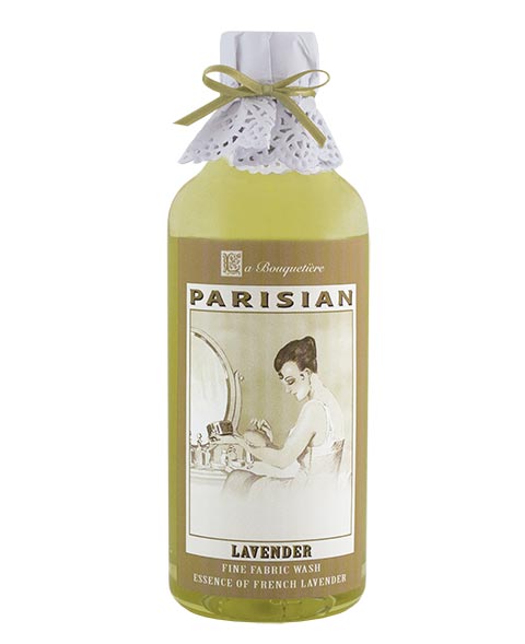 A bottle of La Bouquetiere Lavender Fine Fabric Wash featuring a label with a vintage illustration of a woman gently handling clothes near a washing basin. The biodegradable formula is ideal for hi-efficiency washers.