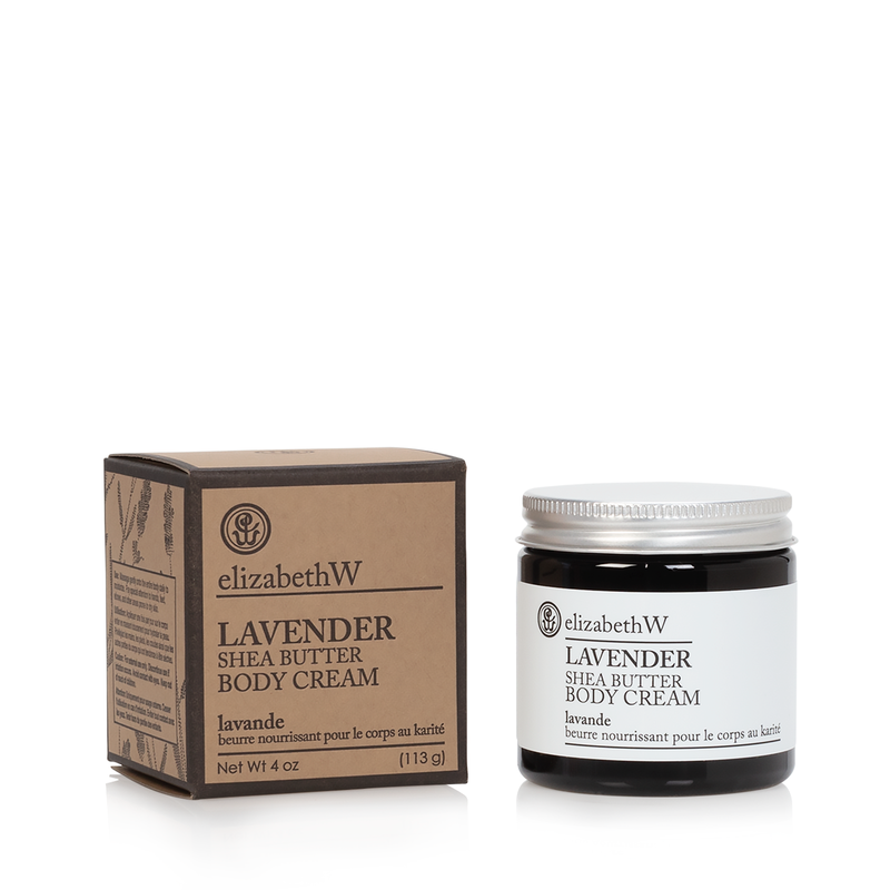 Two elizabeth W Purely Essential Lavender Body Cream products: a cardboard box and a black jar of lavender cream shea butter body cream against a white background. The labels indicate 4 oz (113 g) net content.