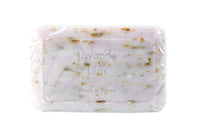 A bar of La Lavande Lavender Lilac - 250gm soap wrapped in clear packaging, labeled "lavande lilas made in france" with visible speckles and herbs embedded, enriched with shea butter for a moistur.