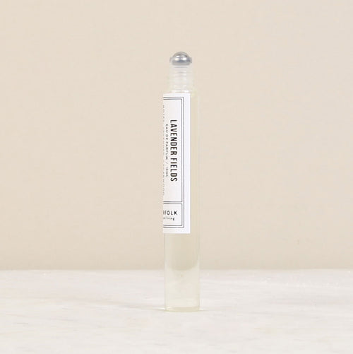 A clear rollerball perfume bottle labeled "Norfolk Natural Living Parfum de l'eau Lavender Fields" standing on a neutral beige background. The oil-based parfum inside appears almost colorless.