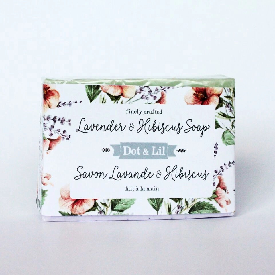 A rectangular Dot & Lil Lavender & Hibiscus bar soap box labeled "lavender & hibiscus soap" from dot & lil, decorated with floral prints featuring pink hibiscus and green leaves. The box is bilingual with French.