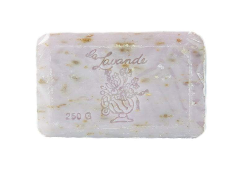 A bar of La Lavande Lavender Lilac soap labeled "La Lavanda" with flecks of herbs embedded within, weighing 250 grams. The soap is translucent and square-shaped, isolated on a white background.