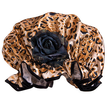 A Fancy Shower Cap - Leopard Print from the brand Shower Caps with a large black rose in the center, draped gracefully, set against a white satin background.