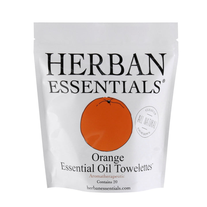 A white package of Herban Essentials Essential Oil Towelettes - Orange. The package has an orange circle with a drawn orange and text that highlights the product is all-natural and contains 20 individually wrapped.