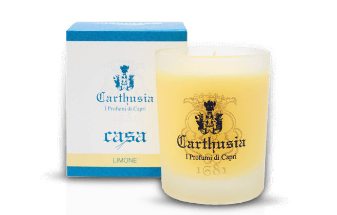 A Carthusia Limone Candle from the Carthusia I Profumi de Capri collection, beside its blue and white packaging featuring a coat of arms and the text "i profumi di capri.