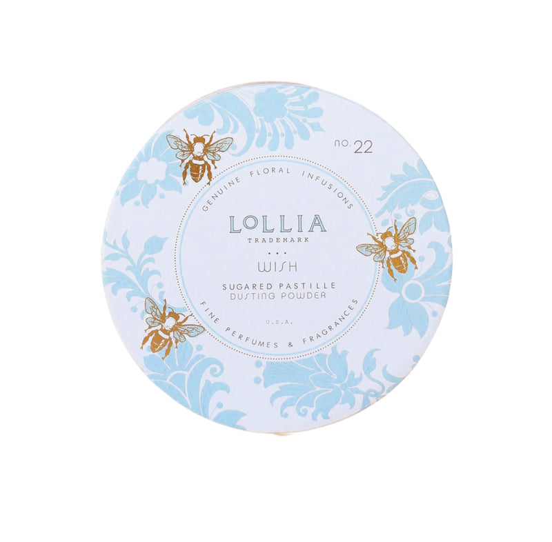 A circular container of Margot Elena's Lollia Wish Dusting Powder, featuring a pale blue and white design with gold and blue floral motifs, and text details about the "Wish" fragrance.