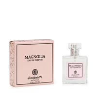 A bottle of elizabeth W Signature Magnolia Eau de Parfum 1.7 fl oz next to its pink packaging box marked with floral patterns. The bottle is clear with a silver cap and the label matches the box.