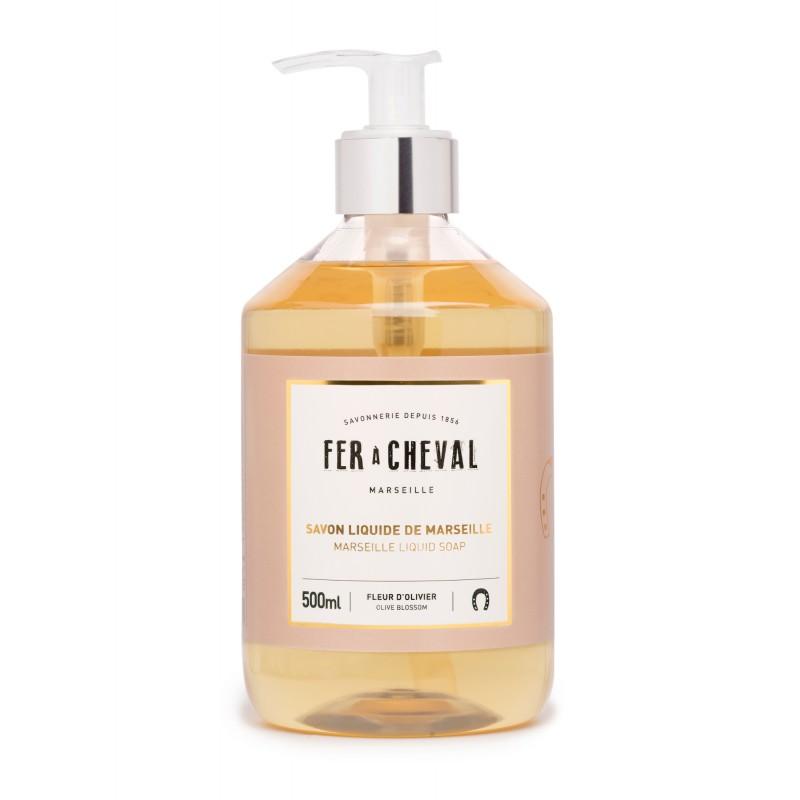 A clear bottle of Fer à Cheval Marseille liquid soap with a pump dispenser, labeled in elegant white and gold text, containing 500ml of orange-amber colored soap enriched with natural ingredients.