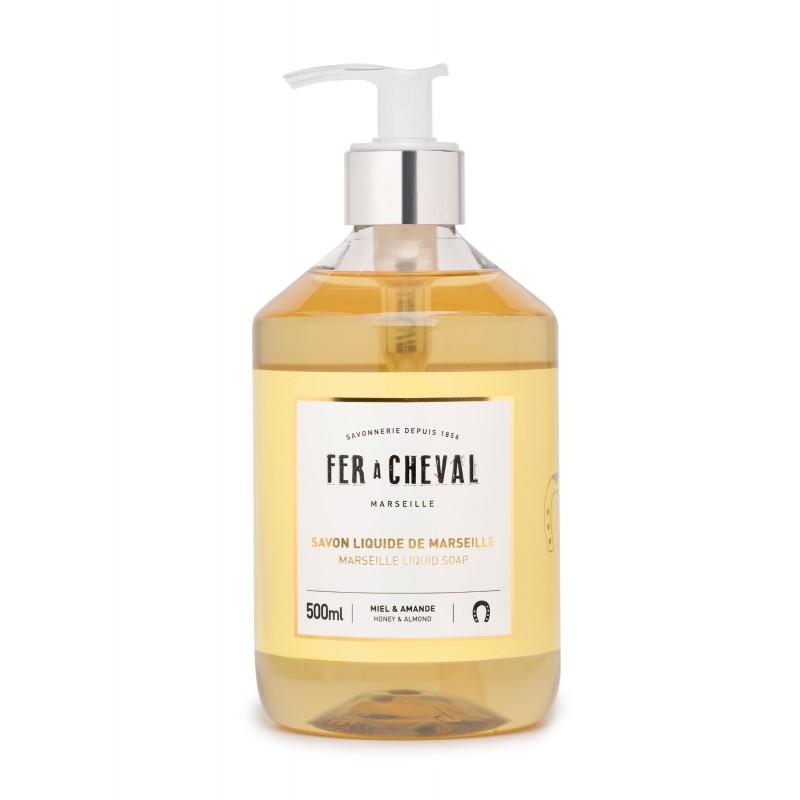 A transparent bottle of Fer à Cheval Marseille Liquid Soap Honey & Almond 500ml with a pump dispenser, labeled in yellow and white against a white background, featuring natural ingredients.