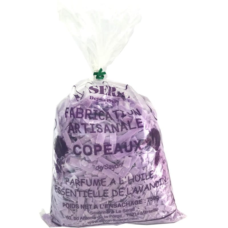 A sealed transparent plastic bag containing purple French Soaps Ltd. Savon de Marseille Lavender Soap Flakes shavings, labeled in French as artisanal and oil-perfumed, tied at the top with a green twist tie.