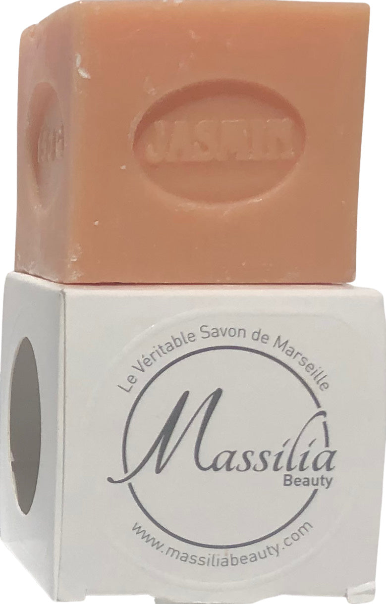 A peach-colored bar of Massalia Beauty 150gr Jasmine Cube Soap for acne-prone skin resting on top of its white packaging box labeled "Made in Provence" with the website displayed.