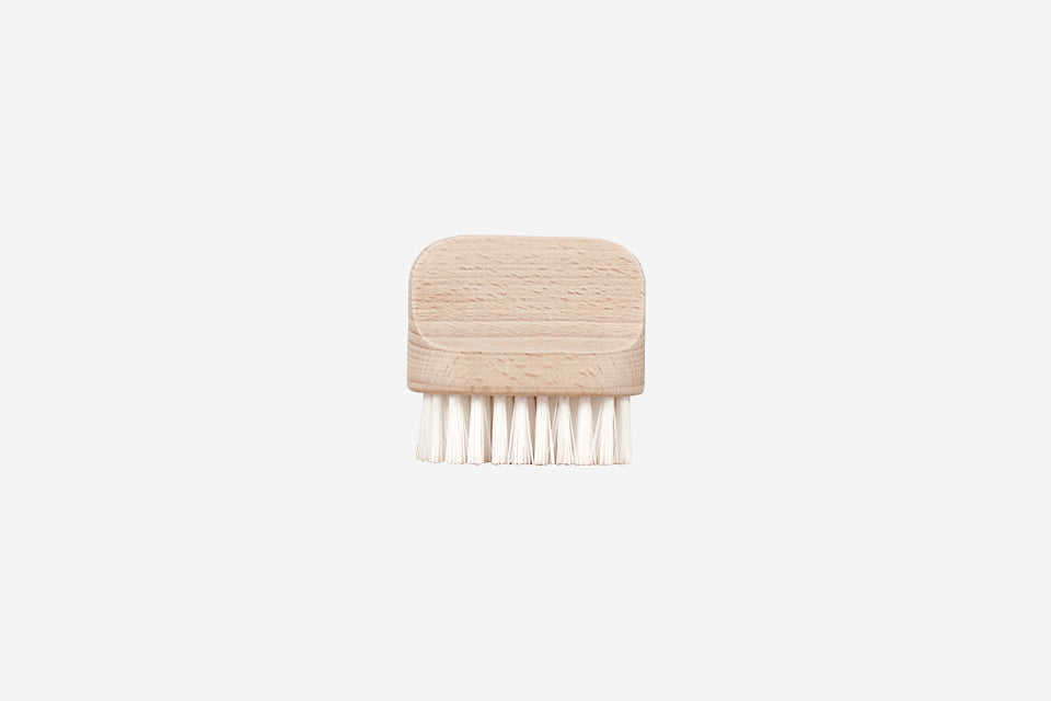 A small, wooden Andrée Jardin "Canot" Vegetable Brush Medium with stiff, white bristles, isolated on a white background.