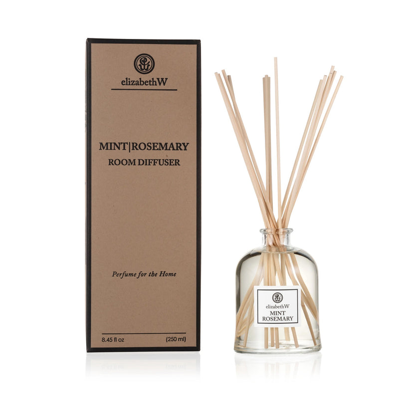 The elizabeth W Purely Essential Mint-Rosemary Diffuser with its environmentally friendly packaging. Glass bottle with reeds inserted on the right, and tall brown box labeled with product details on the left, isolated on