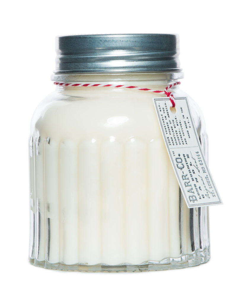 A Barr-Co. apothecary jar with a grey metal lid containing a Barr-Co. Original Scent soy wax candle, adorned with a decorative red and white twisted string and a label. The background is pure white.