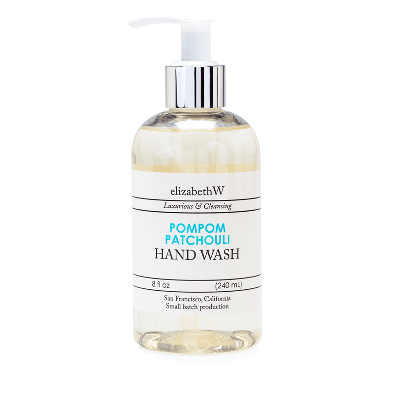 A clear plastic bottle of elizabeth W Small Batch Apothecary Pompom Patchouli Hand Wash with a pump dispenser, labeled "luxurious & cleansing." The bottle contains 8 oz (240 ml) of.