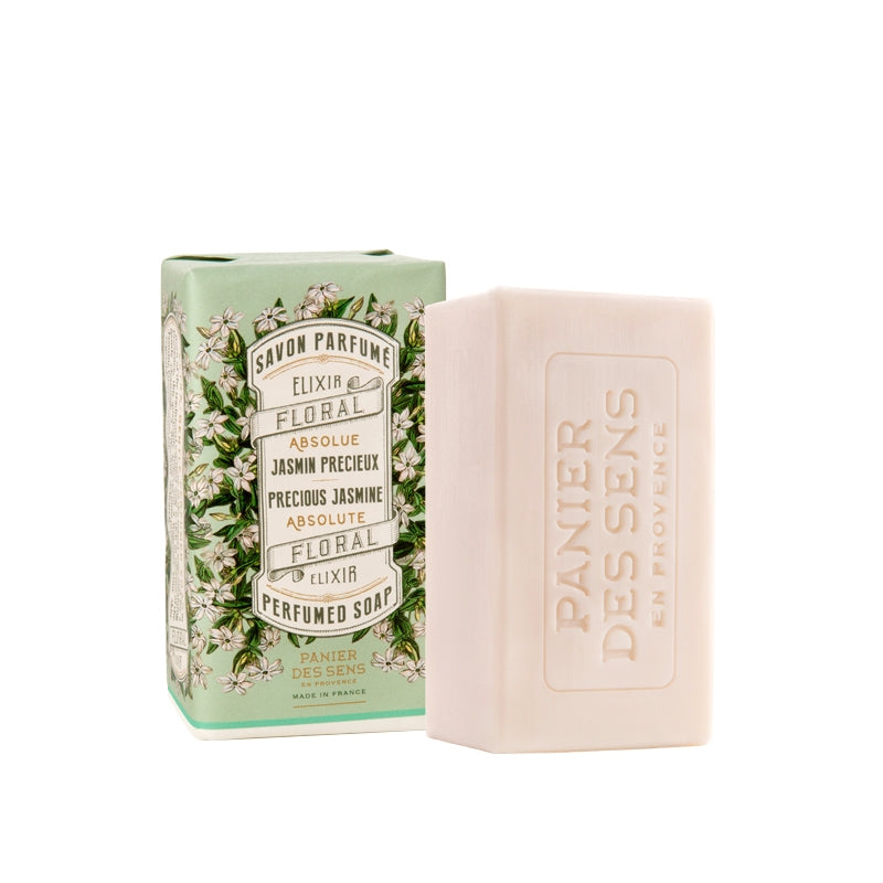 A bar of Panier Des Sens Precious Jasmine Perfumed Soap in a floral packaging, featuring the text "savon parfumé absolu de Jasmine Grandiflorum" and botanical illustrations on a pale