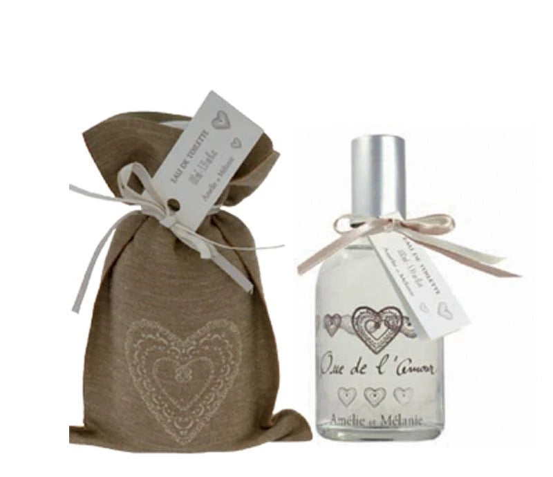 Two wedding favors: a burlap sack with a heart design and a tag, and a bottle of Lothantique's "Amelie et Melanie Que de l'Amour Eau de Toilette" with a heart design, both tied with ribbons.