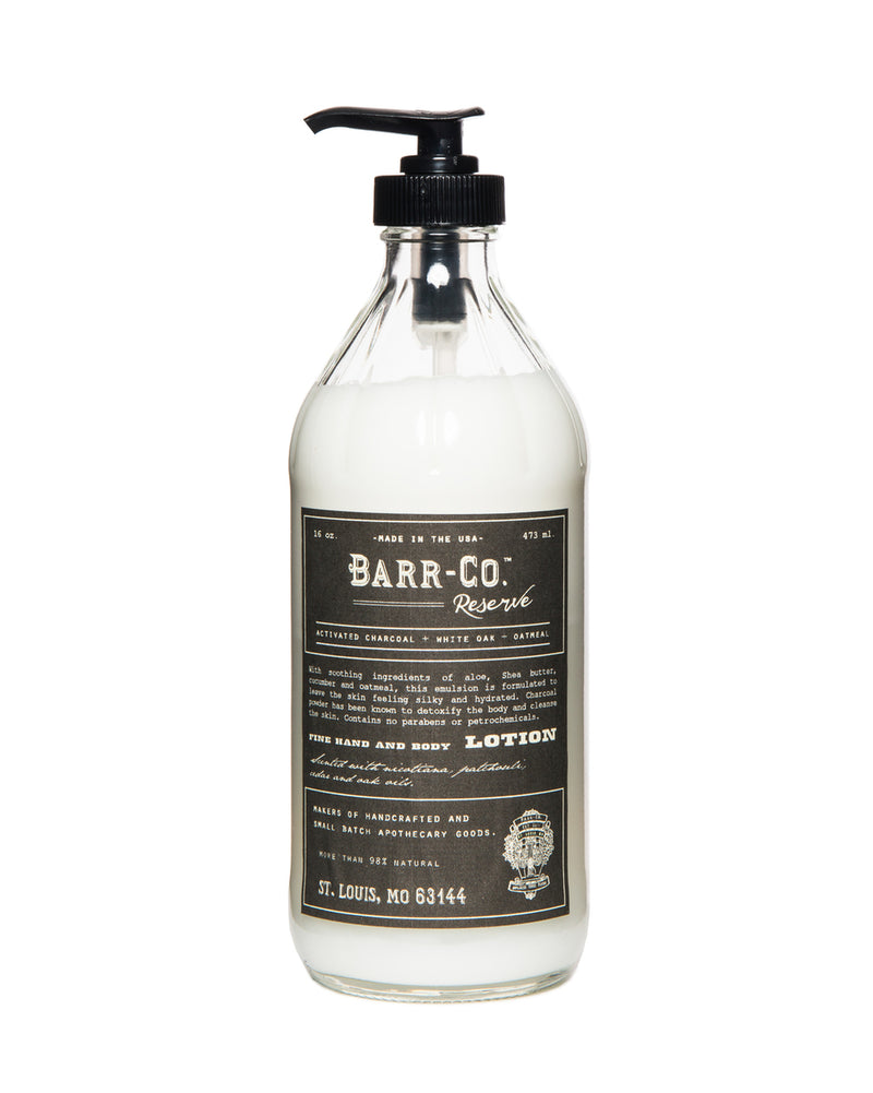 A transparent bottle of Barr-Co. Reserve Shea Butter Lotion with a black pump dispenser, featuring vintage-style black and white labeling and infused with natural plant extracts.