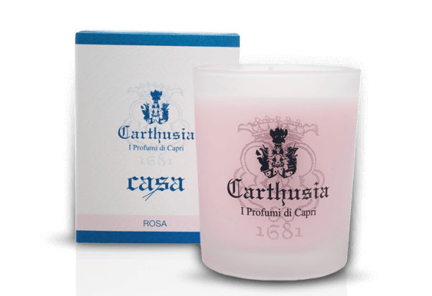 A Carthusia I Profumi di Capri Rosa Candle with a pink label and the brand logo, placed next to its blue and white packaging box. The text "I Profumi di Capri" is visible on.