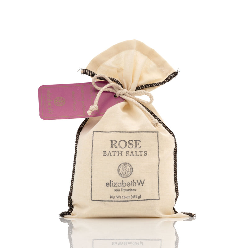 A small, fabric drawstring bag labeled "Elizabeth W Signature Rose Bath Salts" by elizabeth W, San Francisco, with a net weight indication and secured with a ribbon. A pink rectangular tag is attached to