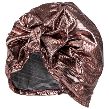 A shiny, metallic rose gold Fancy Shower Cap - Rose Lamé Turban with a large decorative bow on top, crafted from Rose Lamé fabric and designed with an elastic band to fit snugly around the head by Shower Caps.