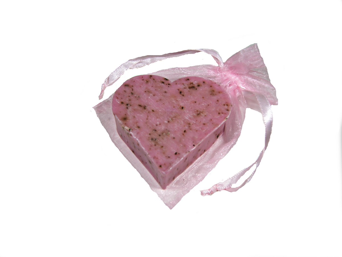 A Massalia Heart Soap - Rose Exfoliating with black specks, infused with essential oils, wrapped with a translucent pink ribbon, on a white background. Made by Made in Provence.