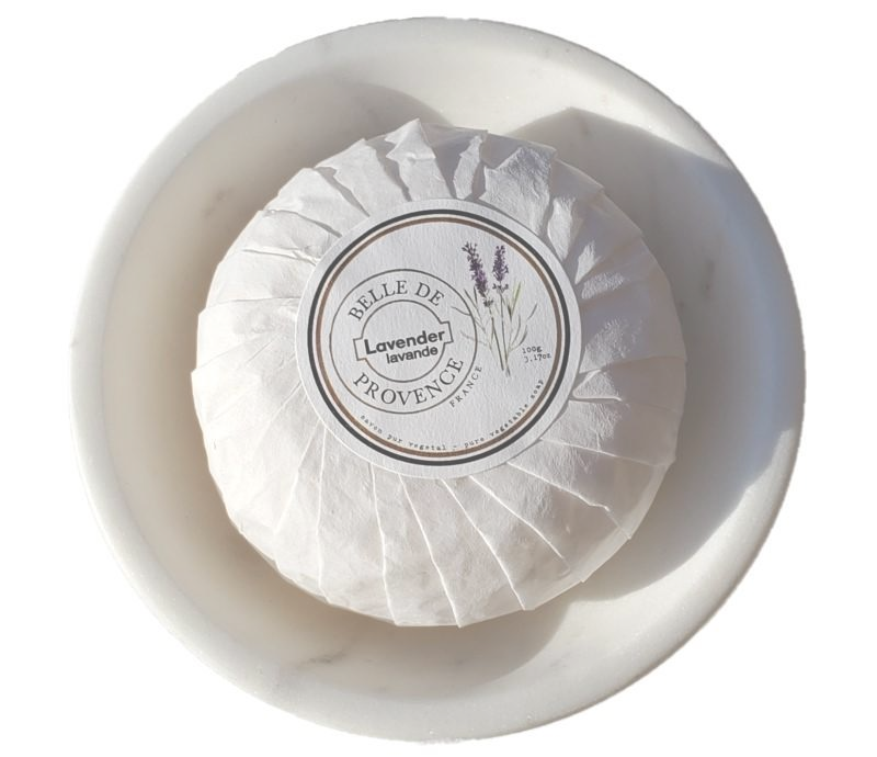 Round bar of Belle de Provence 100g Lavender Soap by Lothantique wrapped in white paper, labeled "huile de lavender Provence," presented in a shallow white dish against a bright background.