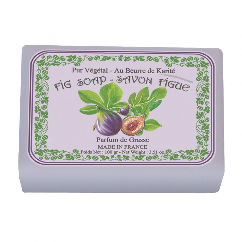 A bar of Le Blanc Fig Wrapped Soap wrapped in light purple packaging displaying images of figs and leaves with text indicating shea butter content and manufacture in France.
