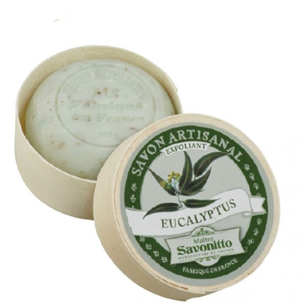 A round bar of Maitre Savonitto Eucalyptus Exfoliating Soap inside an EA2G natural wood container with a labeled lid displaying the product details. The soap is speckled, indicating it contains exfoliating ingredients.