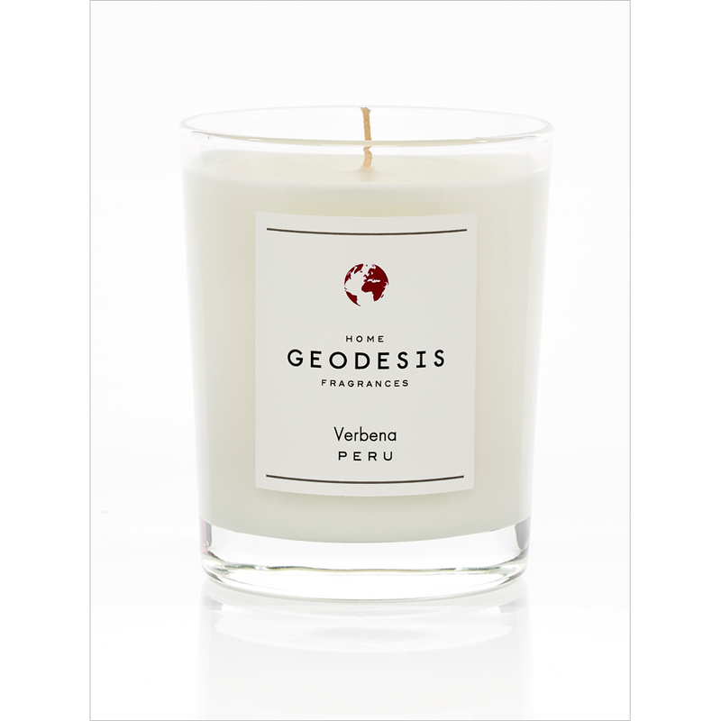 A Geodesis Verveine 180gm scented candle in a clear glass jar with a white label featuring the text "Peru with Verbena" below an emblem of a globe. The candle has a single, unlit wick.