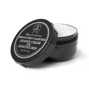 Round black container of Taylor of Old Bond Street Jermyn Street Collection Sensitive Skin Shaving Cream 150g with lid open, showing white cream inside, isolated on a white background.