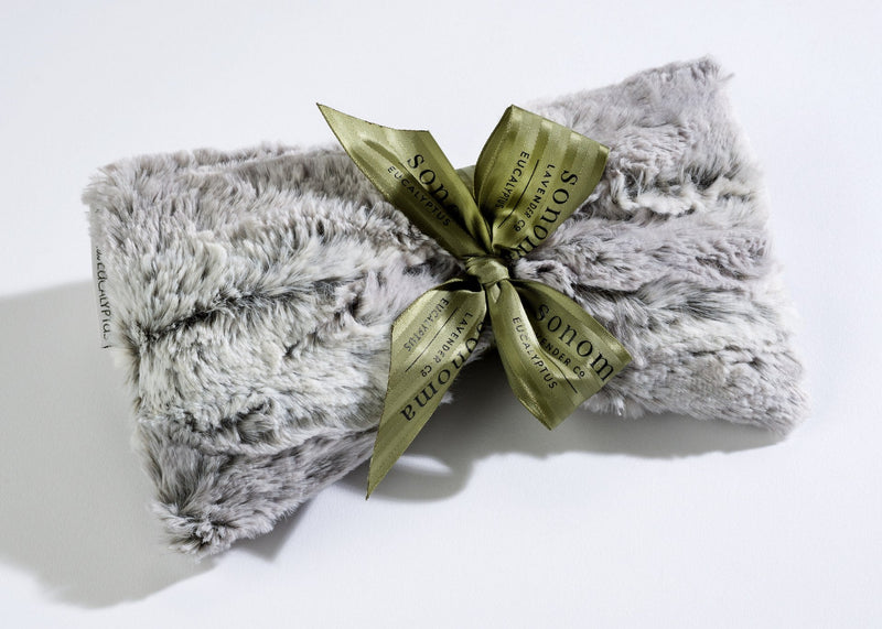 A Sonoma Lavender Sonoma Eucalyptus Silver Fox Sinus Mask neatly folded and tied with a luxurious golden ribbon, displaying the text "snowe" on a white background, designed to relieve tension.