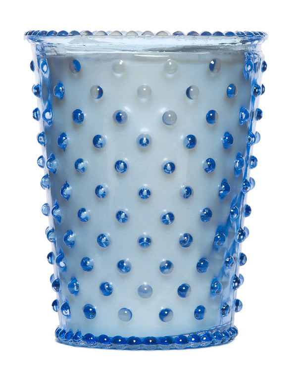 A Simpatico NO. 64 Lavender Hobnail Glass Candle featuring a pattern of raised blue dots on a frosted white background, isolated against a white backdrop with a lavender candle.