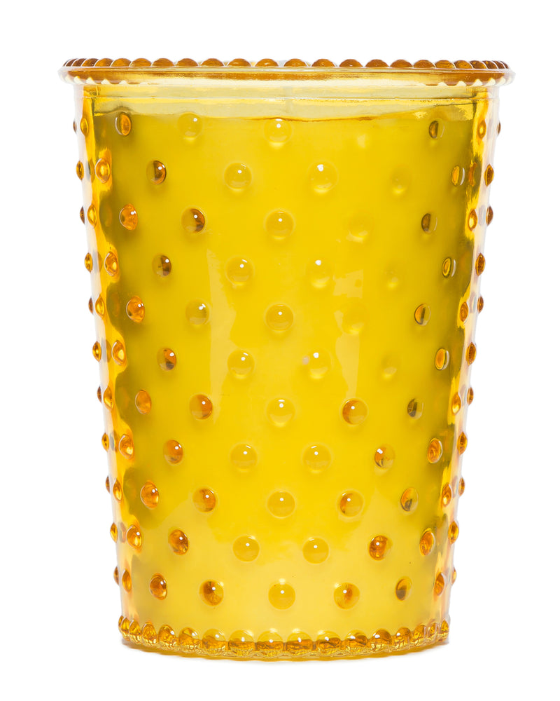 A vibrant yellow Simpatico NO. 97 Meyer Lemon Hobnail Glass Candle with raised dot texture and a wavy rim, isolated on a white background.