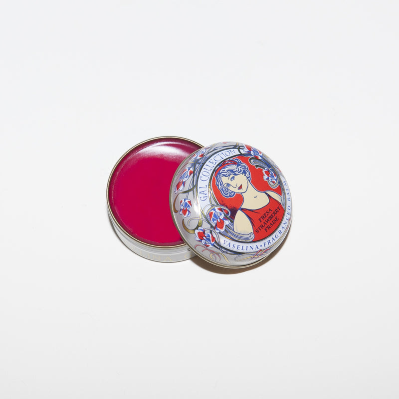 A small, open round tin of Perfumeria Gal Madrid Fragranced Lip Balm- Strawberry with a vibrant red product inside. The lid, decorated with a vintage-style label featuring a cartoon nurse, sits beside the base on a white background.