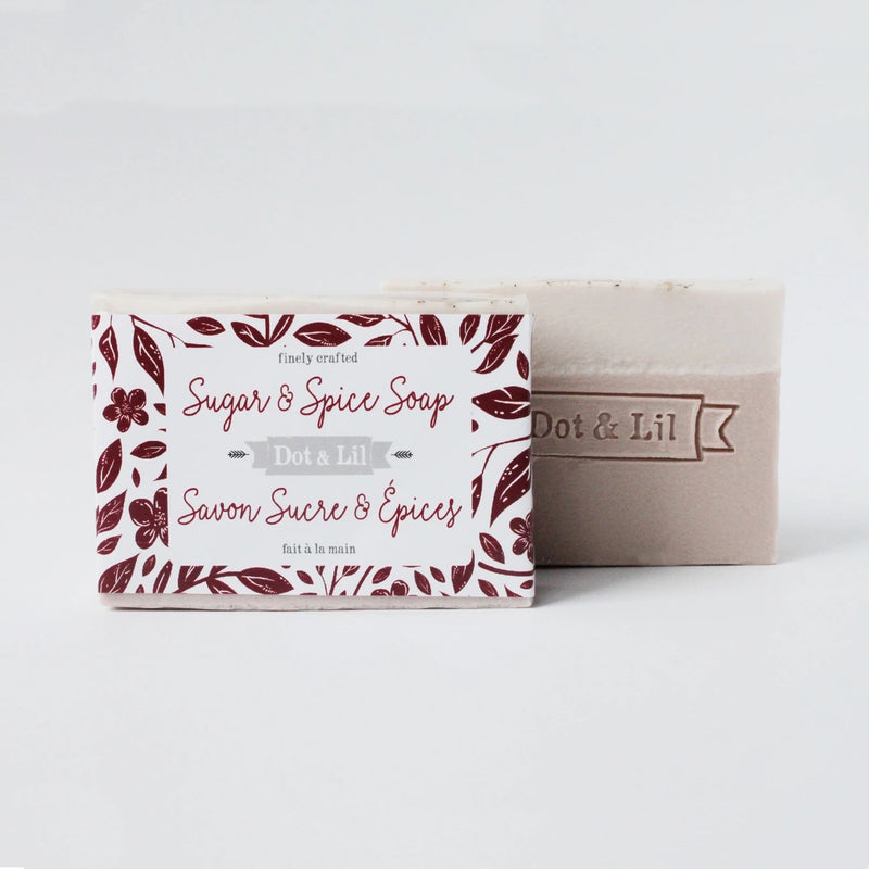 A bar of Dot & Lil Sugar + Spice Bar Soap, next to its packaging. The box features a floral design with burgundy accents on a white background.
