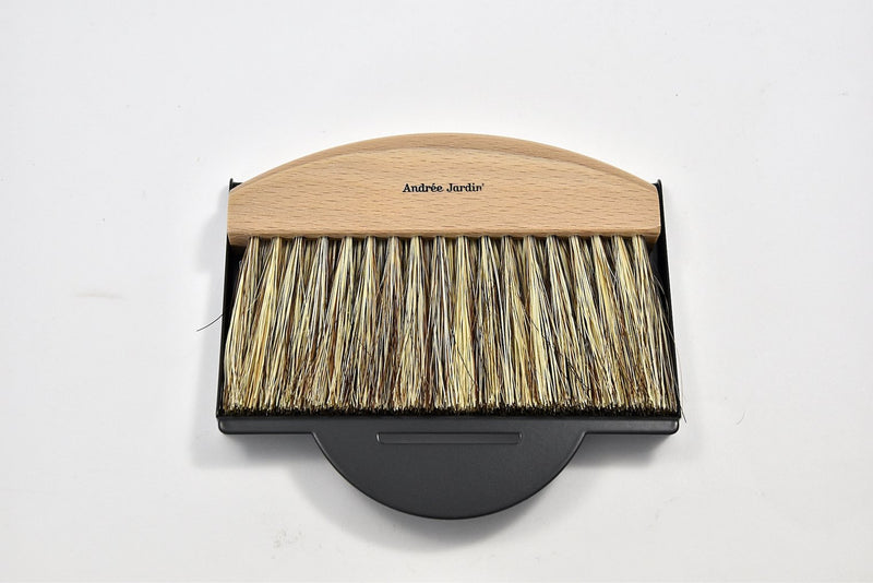 A Andrée Jardin Mr. & Mrs. Clynk Natural Table Brush & Dustpan Set - Black with a curved light wood handle and dense, 100% natural fibers bristles, branded with "andrée jardin," resting on a white background.