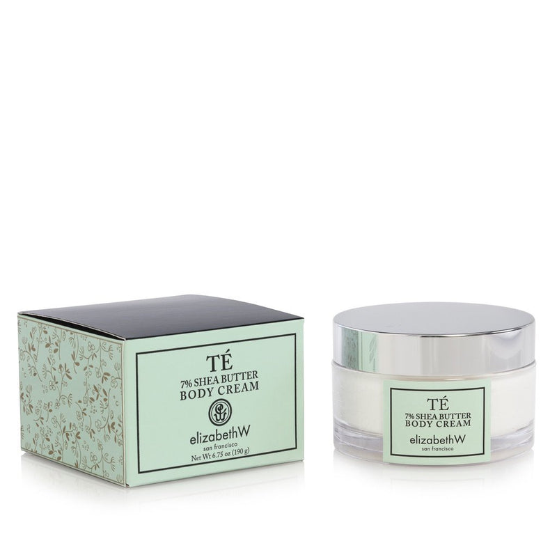Elizabeth W branded elizabeth W Signature Té Body Cream in a glass jar next to its matching green and floral print box, labeled as 75% shea butter body cream.