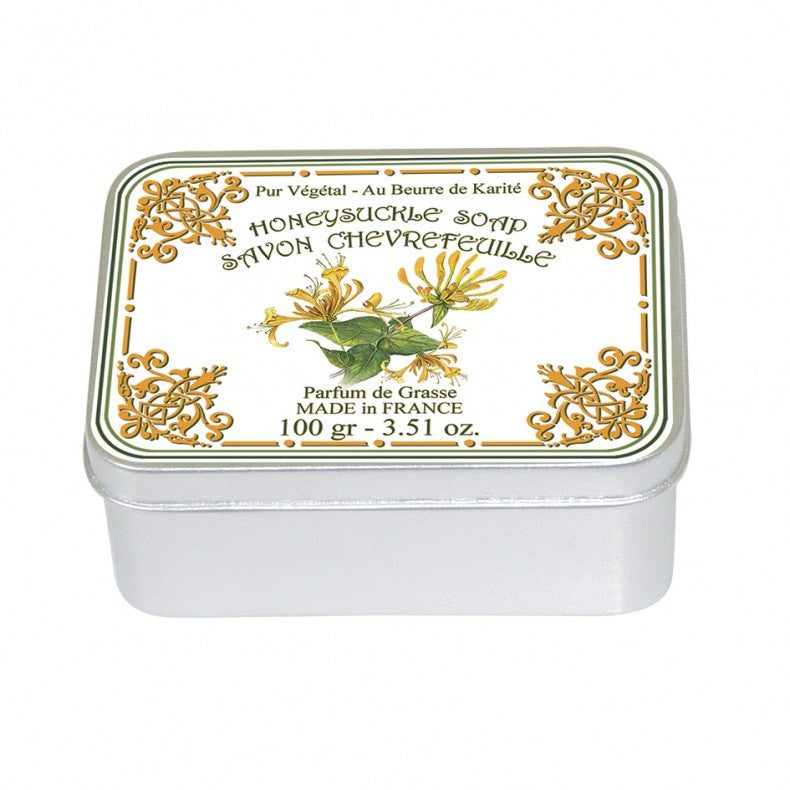 A rectangular tin of Le Blanc Honeysuckle 100gm soap, featuring ornate gold and green designs with floral elements on the lid, labeled in French and English, stating it is made in France and weighs
