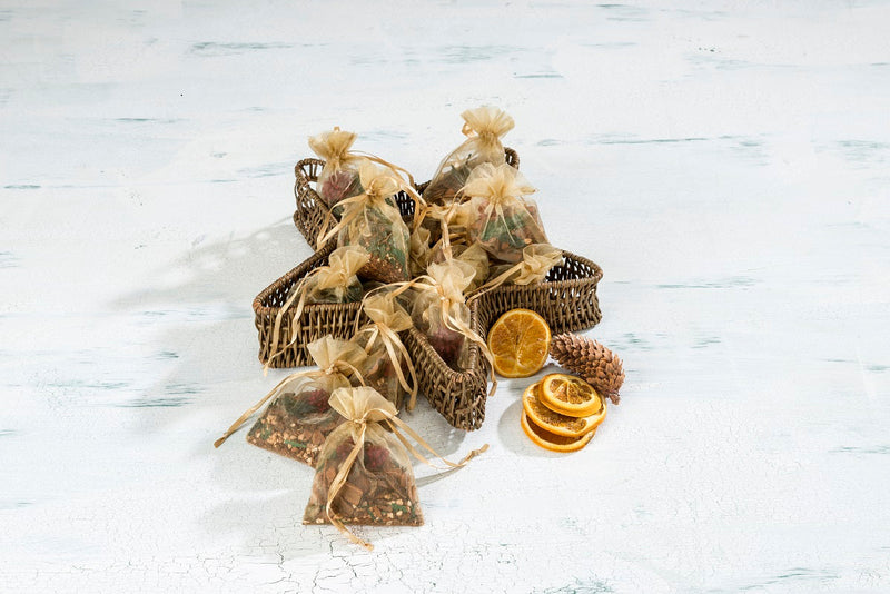 Festive holiday Sonoma Lavender gift bags filled with dried fruits, nuts, and pine cones on a rustic white wooden background.