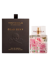 A "Margot Elena TokyoMilk Dead Sexy Elevated Embossed Eau De Parfum" bottle next to its packaging, featuring a skull and crossbones design on a dark background with pink liquid visible.