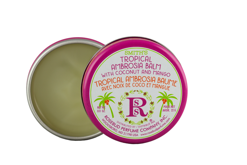 A container of Rosebud Perfume Co.'s Smith's Rosebud Tropical Ambrosia Lip Balm is open to reveal its contents, with a vibrant pink and green label featuring coconut and mango imagery. The lid is angled to show the product name.
