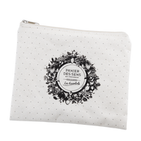 A small, white fabric pouch with a black floral design and text "Panier Des Sens Lavender Travel Pouch - les essentiels" enclosed in a circular frame, against a plain background, infused with Panier Des Sens.