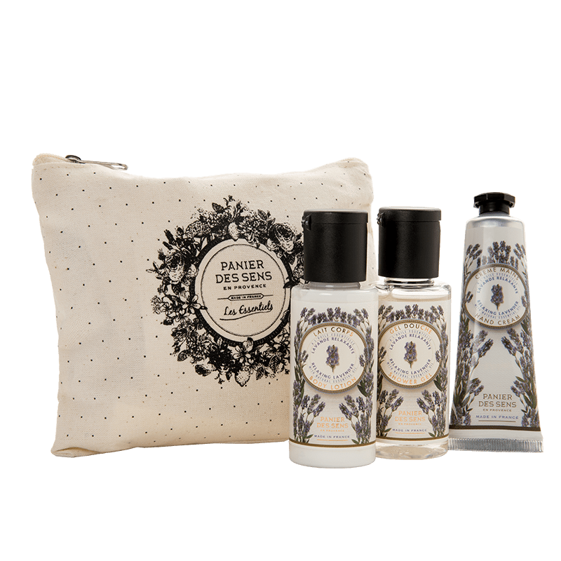 A collection of Panier Des Sens Lavender Travel Pouch body care gift set including a cream tube and two small bottles, presented next to a canvas pouch with a decorative black floral print on a green background.