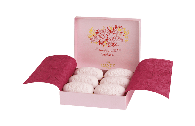 A pink Rancé Classic Soap - Tuberose box containing six white, intricately patterned bath bombs, displayed with the box lid open and the lid's interior featuring a floral design and text.